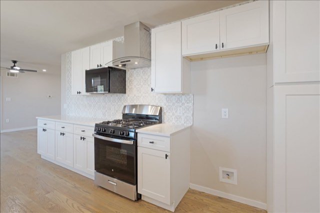 White kitchen with stainless gas range and range hood